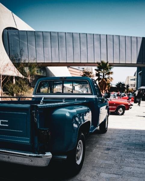 A turquoise pickup truck parked under a filling station canopy.